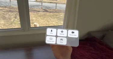 Vue subjective d'un utilisateur de Meta Quest utilisant le suivi des mains : un menu virtuel transparent "Expanded Quick Actions" flotte au-dessus de la paume, affichant les icônes Mute, Recenter, Record video, See your surroundings et Menu.